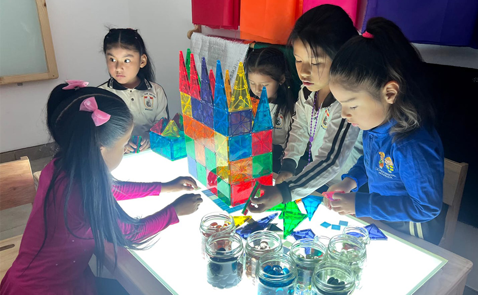 Five-year-old girls closely observe a root using a digital microscope connected to a laptop at school Modelo San Antonio, Perú. 