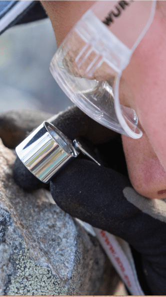 Person inspects rock using a loupe