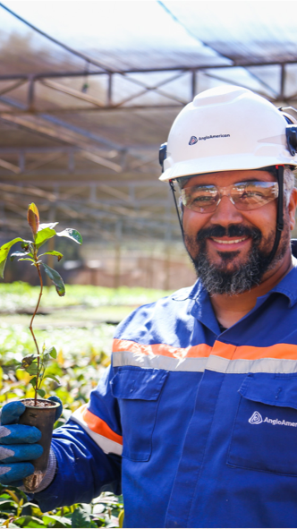 Man smiles while holding a sapling